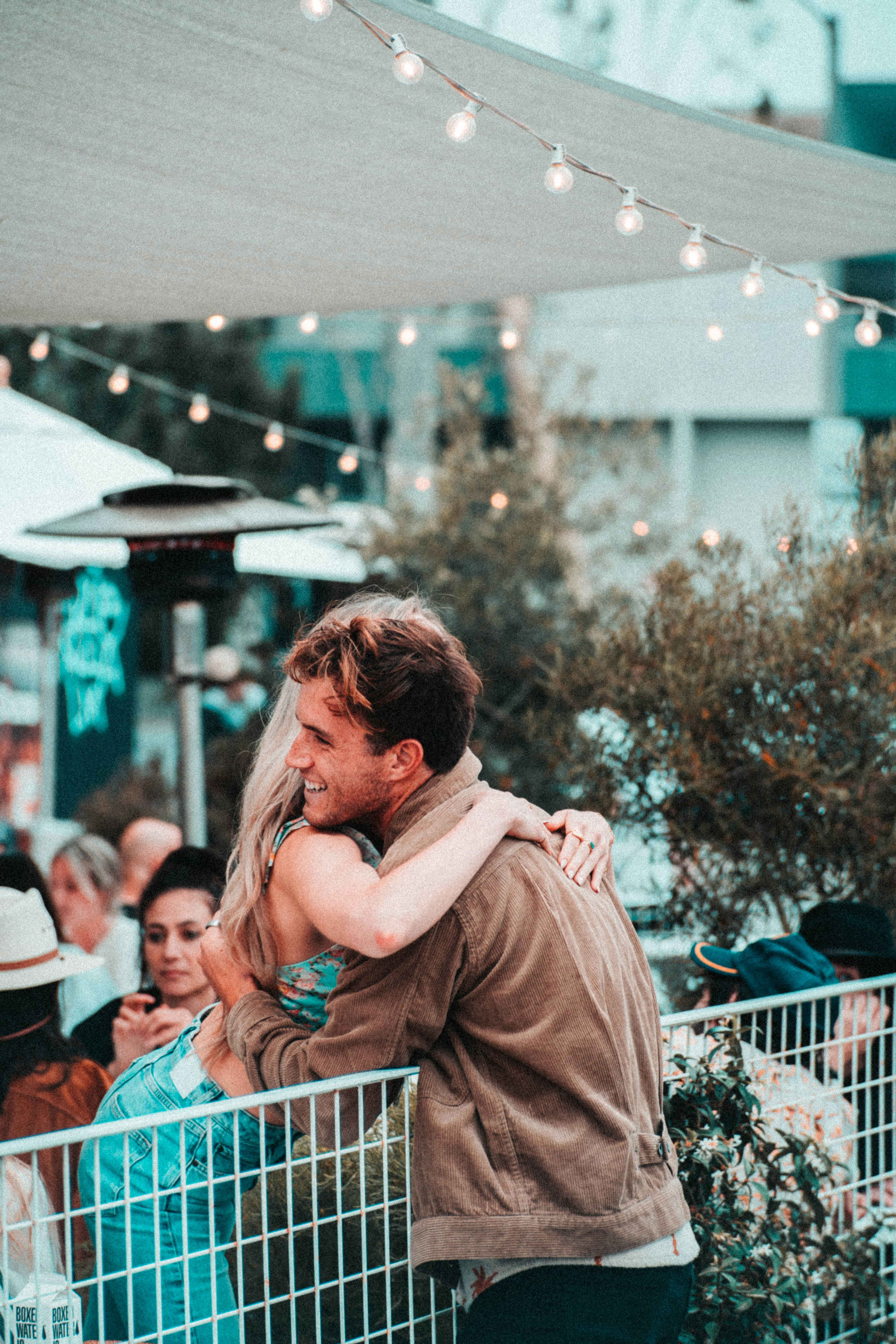 man in brown coat kissing woman in white shirt